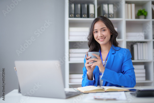 Successful Asian businesswoman smiling holding coffee cup at office. Confident Asia businesswoman standing happily in the office.