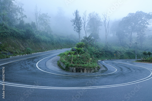 Long winding mountain road leading through rural countryside in Munnar Kerala India. Mountain highway with sharp hairpin turns on a fogy rainy day. Dangerous road to drive accident prone. photo