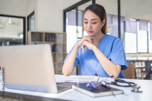 Happy doctor Portrait of young asian woman nurse or doctor smiling using a laptop writing content at consultation	