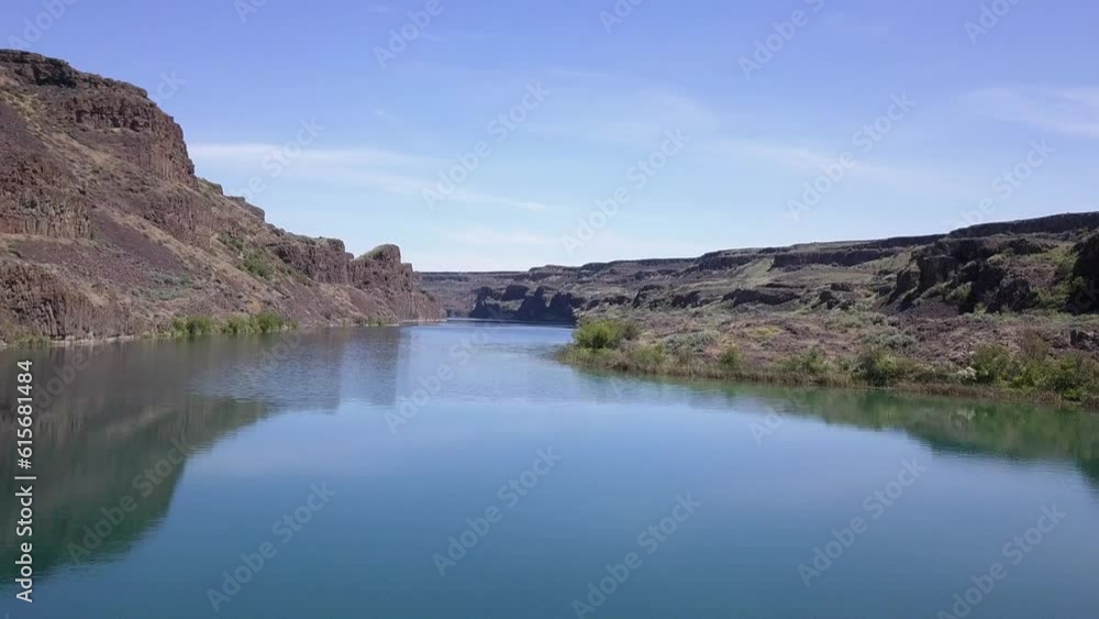 Low POV skims along surface of deep blue lake in rugged, arid terrain Low POV skims along surface of deep blue lake in rugged, arid terrain
