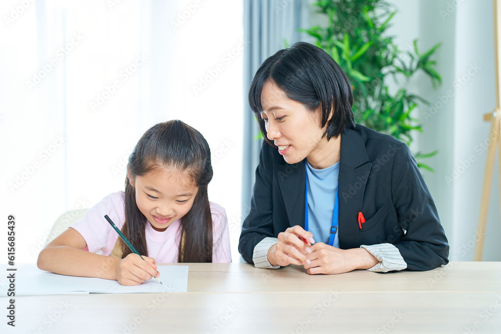 勉強する女の子とサポートするスーツ姿の女性