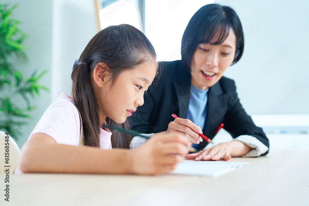 勉強する女の子とサポートするスーツ姿の女性 勉強する女の子とサポートするスーツ姿の女性