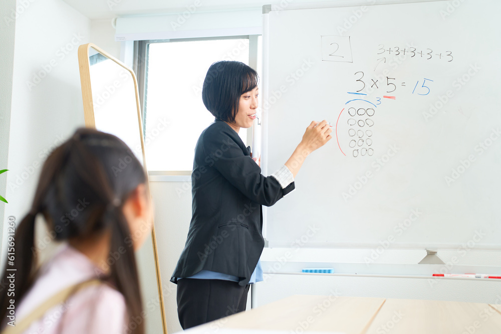 子どもに向かって授業するスーツ姿の女性 子どもに向かって授業するスーツ姿の女性