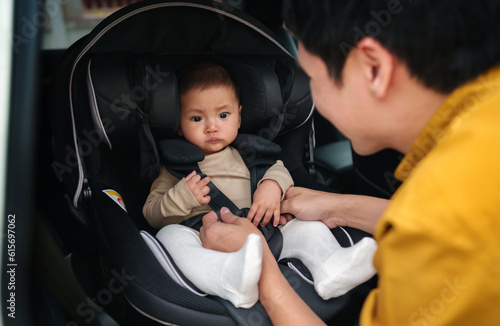 happy father is fastening safety belt to infant baby in car seat © geargodz