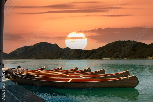 Sunset on the lake with traditional wooden canoe and mountain background, South Korea