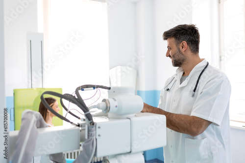 Radiologist setting up the machine to x-ray female patient. Radiologist and patient in a x-ray room. Classic ceiling-mounted x-ray system. Medical equipment