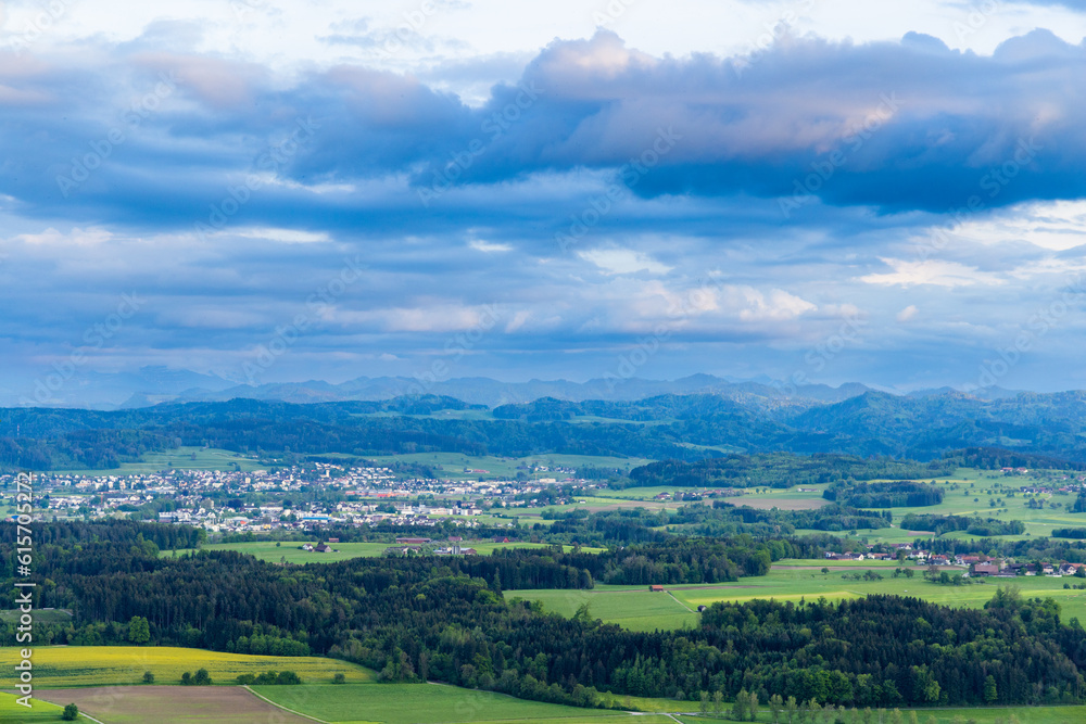 View of a forest, fields and village on the hills against a cloudy sky View of a forest, fields and village on the hills against a cloudy sky