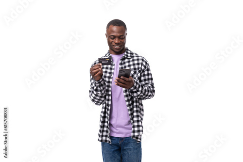 mobile young american man in casual shirt enjoys online payment using smart on white background with copy space