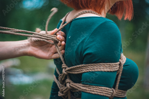 a man ties up a woman in green body and black tights with a natural rope japanese art of aeshetic shibari bandage kinbaku