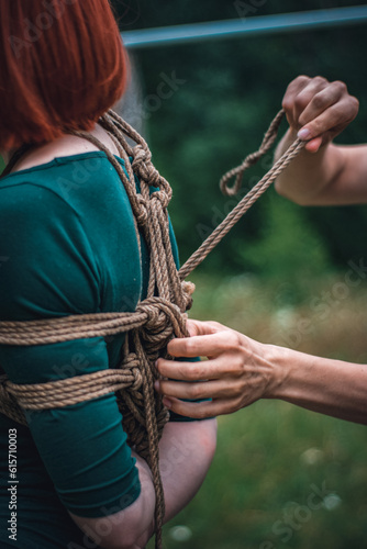 a man ties up a woman in green body and black tights with a natural rope japanese art of aeshetic shibari bandage kinbaku