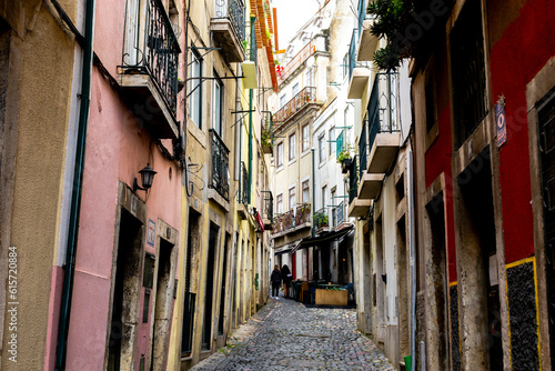 Two young women walk up a narrow street in Lisbon