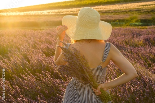Against a backdrop of vivid lavender field, a young lady elegantly stands, her straw hat adding a touch of charm