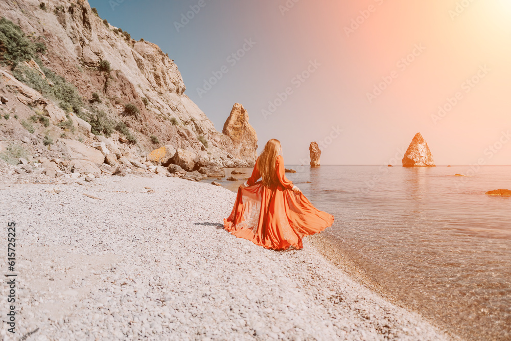 Woman travel sea. Happy tourist in red dress enjoy taking picture outdoors for memories. Woman traveler posing on the rock at sea bay surrounded by volcanic mountains, sharing travel adventure journey Woman travel sea. Happy tourist in red dress enjoy taking picture outdoors for memories. Woman traveler posing on the rock at sea bay surrounded by volcanic mountains, sharing travel adventure journey