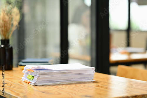 Wooden office desk with pile of documents, laptop and supplies © Prathankarnpap