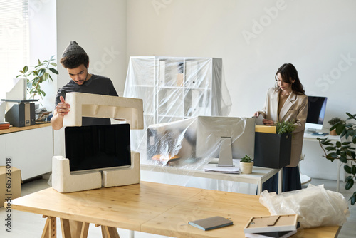 Tapeta Young business people packing things during the move in other office