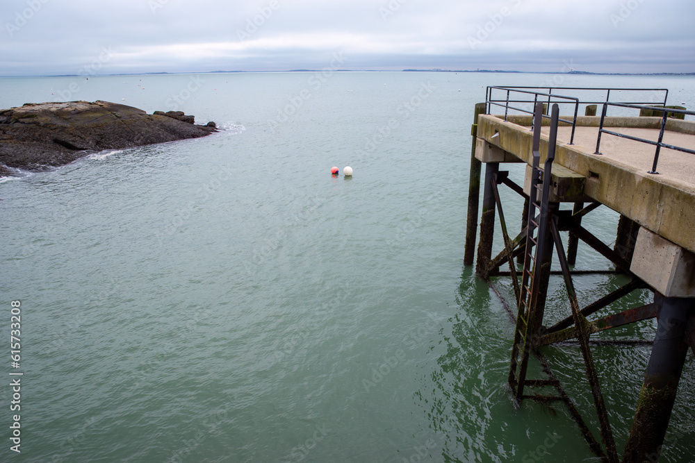 Two buoys float together by a dock along a rocky costline