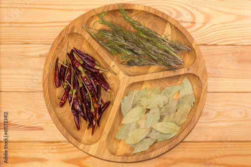 Different dried seasoning on wooden compartmental dish on rustic table photo