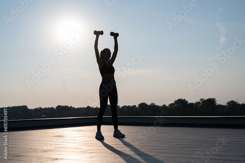 silhouette of a sport girl doing outdoors workout, girl jumping Sunny summer day