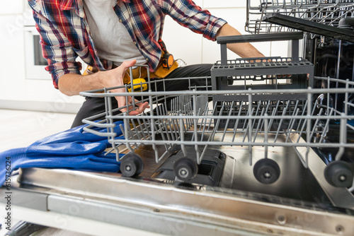 Quadro su tela A new pump for dishwasher in the hands of a men, against the background of a dis