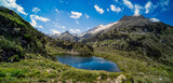 Spectacular, wonderful and evocative landscape of a lake in the Pyrenees surrounded by mountains and snow-capped peaks of Benasque with a clean blue sky with white clouds