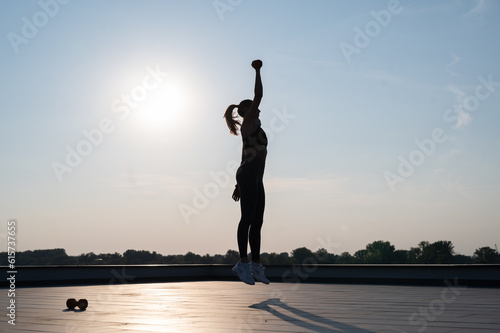 silhouette of a sport girl doing outdoors workout, girl jumping Sunny summer day