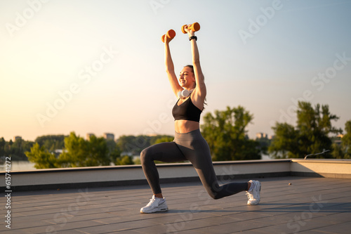 Sport girl doing exercise on sunny summer day, on rooftop