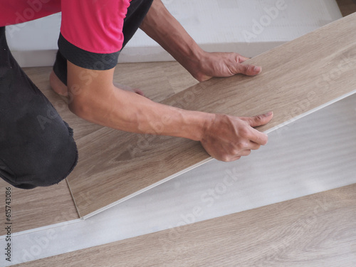 A technician is cutting luxury vinyl floor tiles with a cutter to lay the floor before placing it on the leveling foam. © SimpleBen.CNX