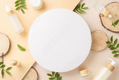 Eco friendly cosmetics concept. Top view photo of empty circle with eucalyptus and bracken branches, wooden podiums and cosmetic containers on isolated two-colored beige background with copy-space