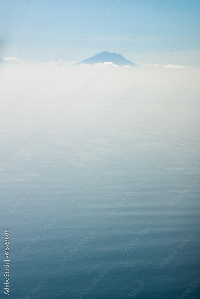 Fototapeta premium bird's eye view of the Agung volcano, minimalistic landscape, only the silhouette of the mountain, clouds and ocean.