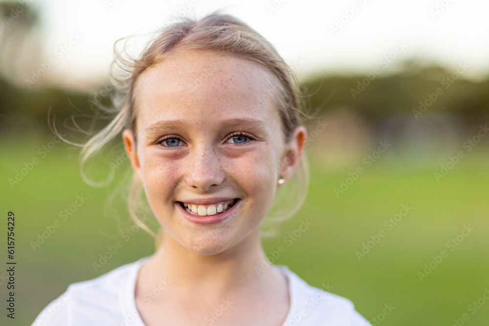 head and shoulders of one blonde-haired blue-eyed child with blurry green background head and shoulders of one blonde-haired blue-eyed child with blurry green background