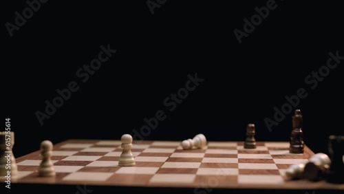 Caucasian Woman's Hand Knocking Down Chess Pieces on Rotating Chess Board. Shot with ARRI Alexa in ArriRaw at 120 fps, exported 23.98 fps QuickTime Apple ProRes 422 HQ. photo