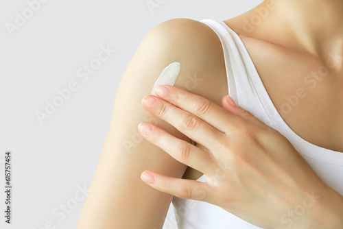 a woman applies sunscreen on the skin of her shoulder. skin care  skin protection concept