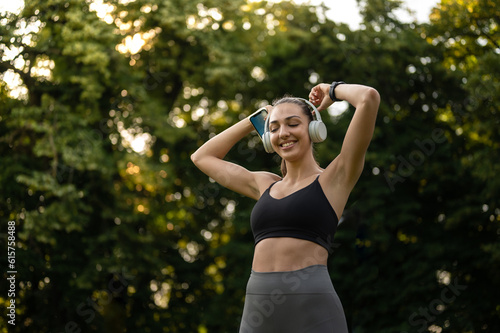 Sport girl with headphones listening to music while prepairing for outdoors workout