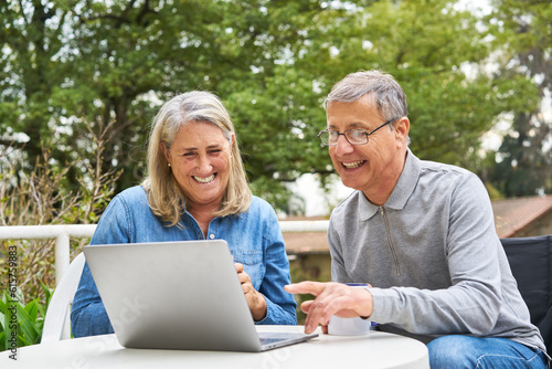 Happy senior couple discussing over laptop in garden