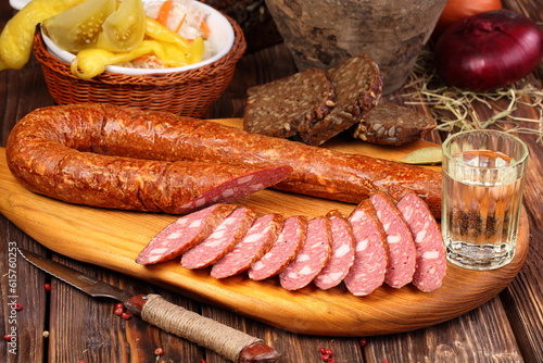 Krakow sausage on a wooden board, decorated with fresh vegetables