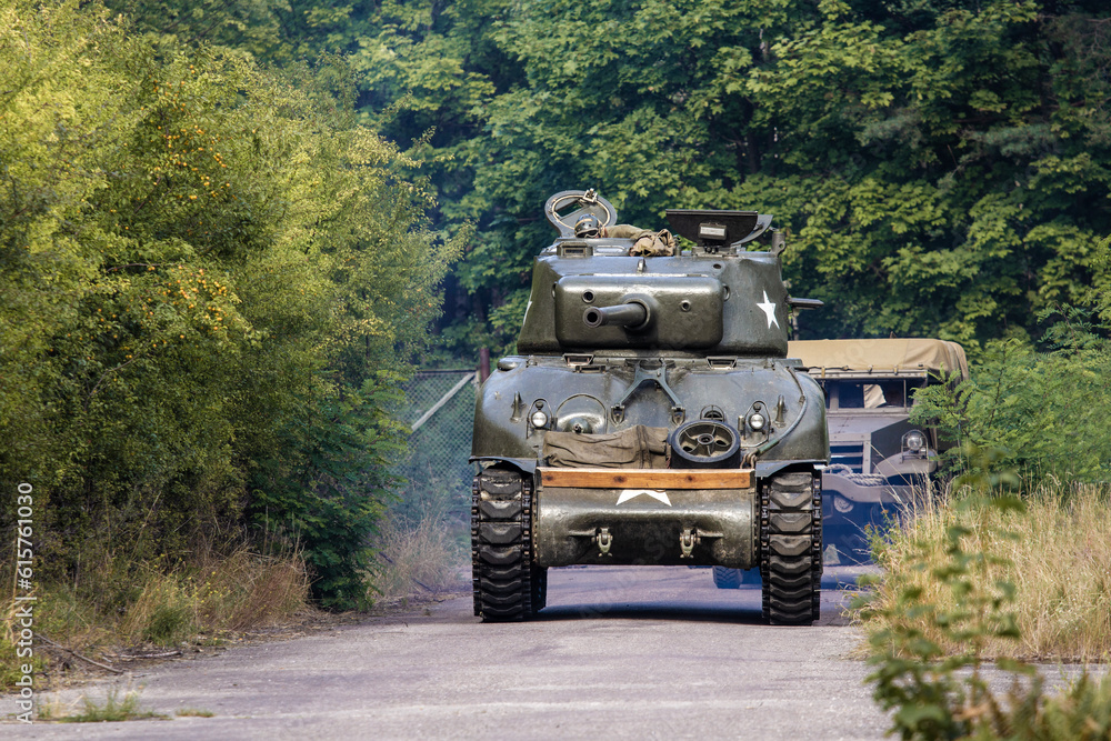 Fototapeta premium An American World War II Sherman drives on the road between the trees.