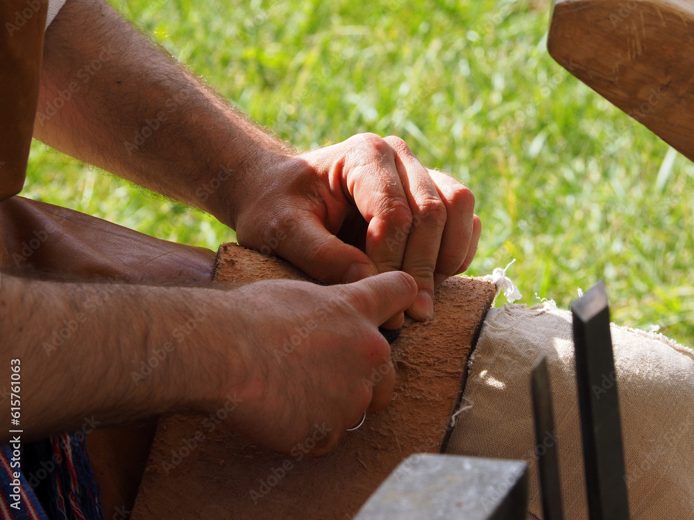 The gunsmith makes flint plates for the bolt of medieval firearms, hands and tools in close-up. Historical reconstruction of a military camp.