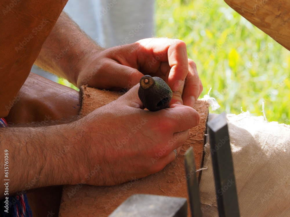 The gunsmith makes flint plates for the bolt of medieval firearms, hands and tools in close-up. Historical reconstruction of a military camp.