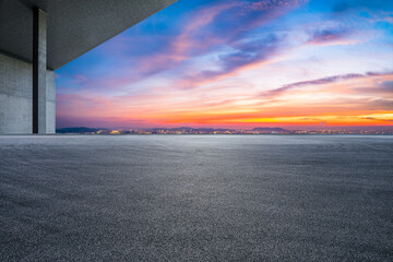 Asphalt road and city skyline with colorful sky clouds at sunset