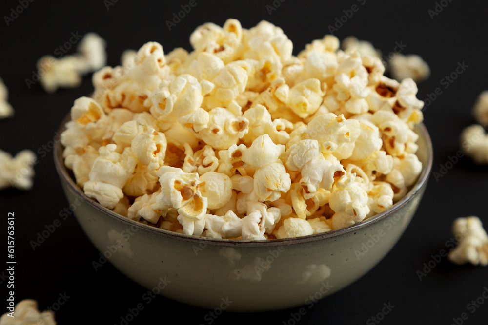 Homemade Buttered Popcorn with Salt in a Bowl on a black background, low angle view. Close-up. Homemade Buttered Popcorn with Salt in a Bowl on a black background, low angle view. Close-up.