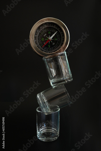 Three transparent glasses stacked with a compass atop in balance concept