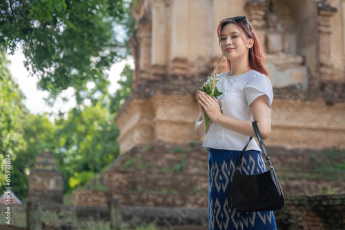 Pretty Asian tourist woman wearing beautiful Modern Thai traditional dress costumes in the ancient Wat Chet Yot Temple (Wat Jed Yod) an Old seven-pagoda Buddhist temple Chiang Mai, Thailand photo
