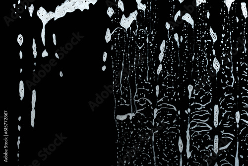 soap foam water drops down glass pane, abstract structure, black background, wash and clean