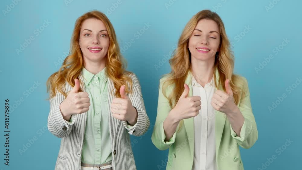 Friends, Yes approval gesture and winner woman sister, say Yes. Excited happy two women, businesswoman satisfied showing approving thumbs up, for victory, deal, success, studio blue background Friends, Yes approval gesture and winner woman sister, say Yes. Excited happy two women, businesswoman satisfied showing approving thumbs up, for victory, deal, success, studio blue background