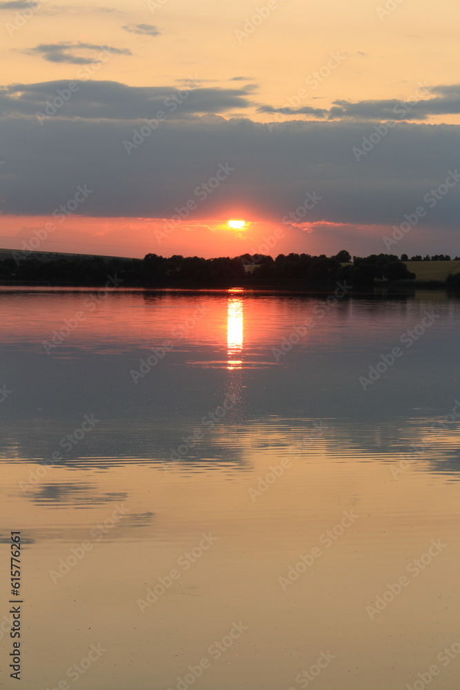 A body of water with a sunset in the background