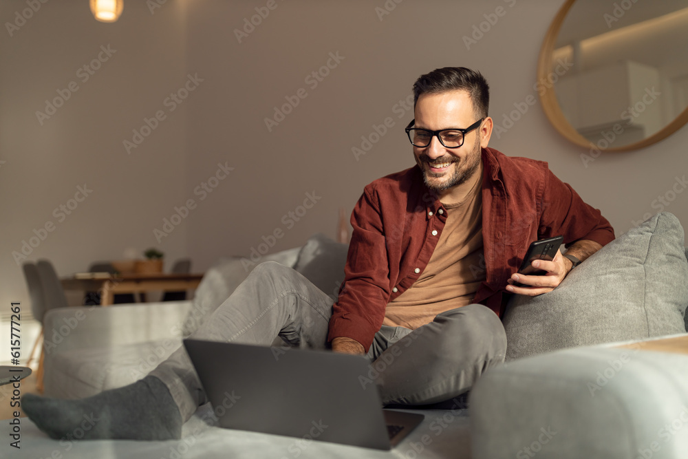 Businessman feeling relaxed, laying on the couch, working over the laptop.