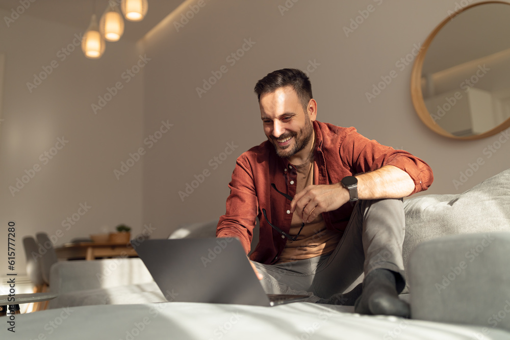 Fototapeta premium Man relaxing at home, watching something online, sitting on the couch.