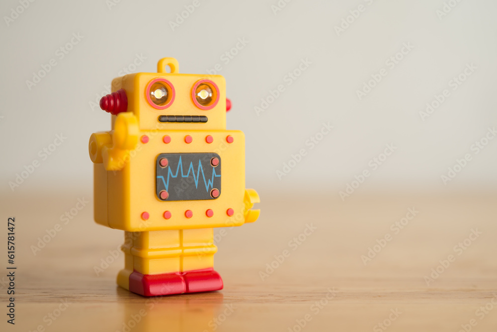Fototapeta premium Yellow cute retro AI robot toy on wooden background copy space. Artificial intelligence (AI), digital future technology, smart brain computer concept.