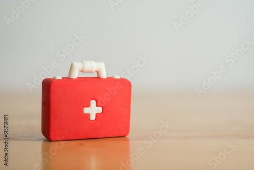 Red first aid bag suitcase toy on wooden background with copy space. First aid kit, healthcare , medical and hospital concept.