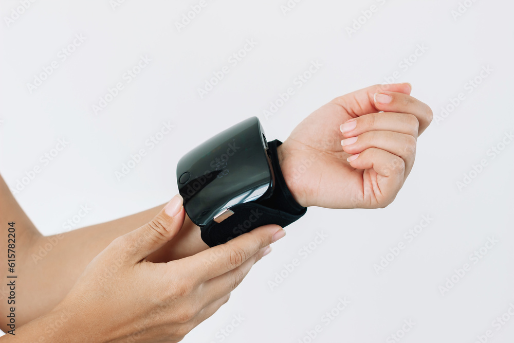 Automatic electronic blood pressure monitor on a woman's wrist isolated on white background. A young woman measures her blood pressure Automatic electronic blood pressure monitor on a woman's wrist isolated on white background. A young woman measures her blood pressure